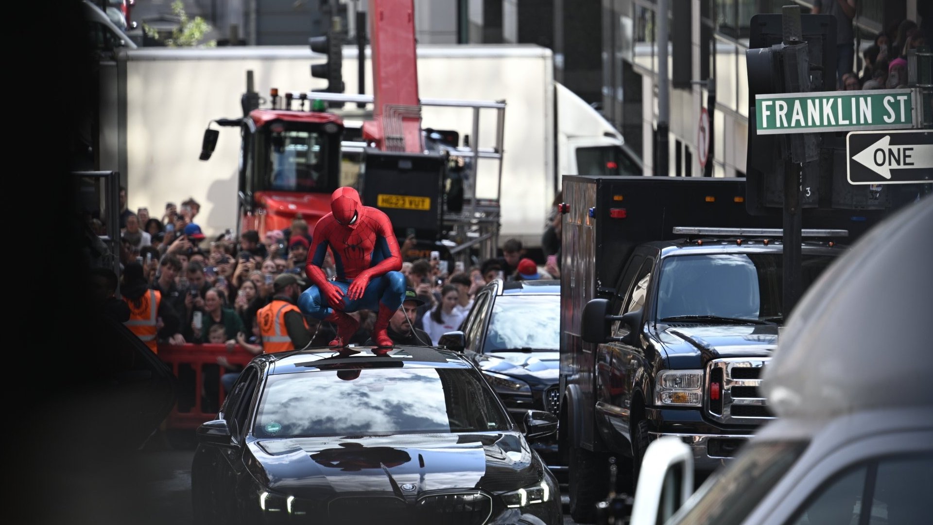 Spider-Man perched on top of a car.